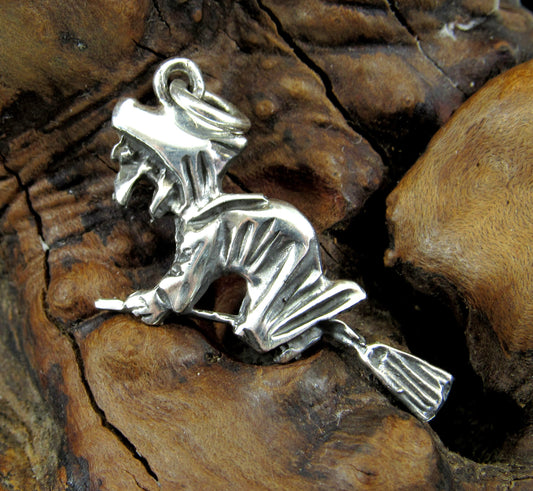 The handcrafted sterling silver witch flying on broom pendant features a wicked witch grasping a broom and flying west.