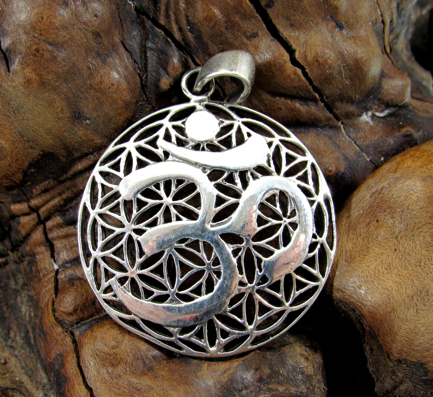 The delicate flower of life design is overlayed with the Hindu Om symbol. The pendant is handcrafted in solid sterling silver.